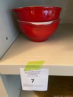 Stacked pair of red Emile Henry ceramic bowls with handles on a shelf.