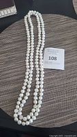 Full view of the long freshwater pearl necklace laid out on a textured surface.