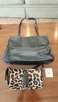 Overview of two Holt Renfrew purses on wooden surface; large black tote purse and smaller leopard print crossbody purse