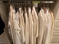 Front view of hangers holding multiple women's tops in light beige and cream tones, size XL, varying materials and sleeve lengths.