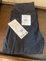Front view of folded black Lululemon pants showing attached tags including size 6 and retail price.