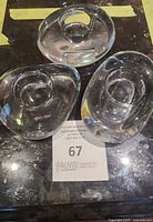 Three clear glass Orrefors River Rocks votive holders arranged grouped on a dark surface with auction lot card
