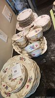 Full set arranged, showing various sizes and types of plates and cups with floral and gold trim.