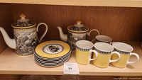 Full view of the set on shelf including teapot, smaller pot, 6 plates, 6 mugs
