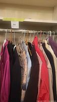 Hanging women's clothing items in various colors and types on a clothing rack.