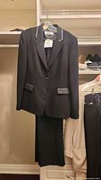 Full view of the black tuxedo suit set hanging in closet showing jacket and pants in size 12.