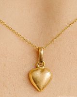 Pendant worn on neck showing gold heart shape and bail