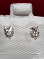 Close-up of two heart-shaped cubic zirconia earrings set in 14K gold, displayed on white textured card.