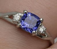 Top-down view showing cushion cut violetish blue tanzanite and adjacent round diamonds