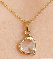 Close-up of the heart-shaped lab diamond pendant worn on skin to show scale and detail.