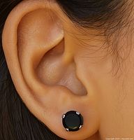 Close up photo showing the black moissanite stud earring worn on the ear.