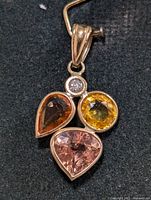 Close-up of pendant showing bezel-set diamond and three colored sapphires
