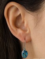 Earring shown worn on model’s ear to indicate scale and drape