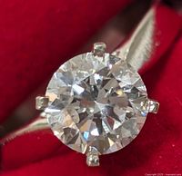 Close-up top view of round brilliant diamond and four-prong setting on red background