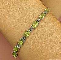 Bracelet worn on wrist showing fit and design with peridot stones in silver.
