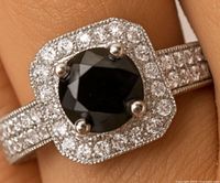 Close-up image of the silver ring with a black diamond center stone and cubic zirconia halo and band stones.