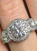 Close-up photo of the certified silver ring worn on finger showing the central moissanite stone surrounded by smaller CZ stones.