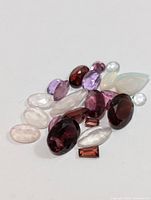 Photo showing a collection of various assorted genuine gemstones with different colors and shapes on a white background.