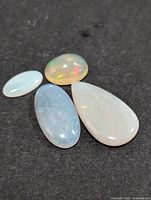 Four polished Australian opals displayed on a black background showing different shapes and color play.