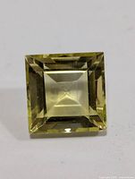 Close-up front view of square cut lemon quartz gemstone showing facets and color.