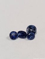 Four genuine tanzanite gemstones placed on a white background showing their color, cut and size variations.