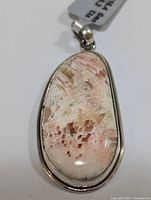 Close-up photo of the silver pendant featuring a large polished agate stone with light pink and brown natural patterns.