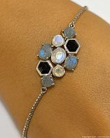 Close-up view of the silver bracelet showing an arrangement of moonstone and labradorite gemstones set in polished silver.