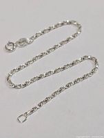 Close-up of silver chain bracelet laid flat showing link pattern and spring ring clasp.