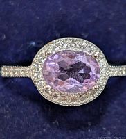 Close-up front view of silver ring with oval faceted light purple amethyst CZ surrounded by small clear stones on a silver band.