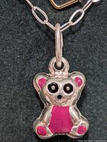 Close-up photo of the teddy bear charm on the silver chain, showing pink enamel accents and black enamel eyes.