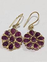 Pair of silver earrings with multiple ruby gemstones arranged in a flower shape, shown from front angle.