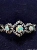 Close-up front view of the sterling silver ring featuring opal and cubic zirconia stones showing the central design.