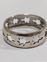 Close-up front angle of silver ring with leaf-shaped cutouts.