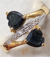 Close-up front view showing two heart-shaped sapphire stones with accent clear stones on band