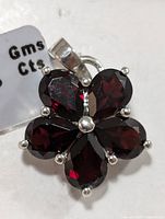 Front view of silver pendant with five dark red garnet stones in a floral design and silver bail