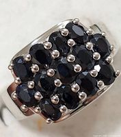 Close-up front view showing deep blue oval faceted sapphires in prong settings on silver ring.