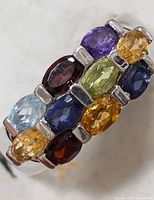 Close-up front view of multi-gemstone ring showing arrangement and variety of colored stones.