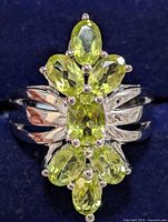 Front view of the silver ring showing peridot stones arranged in a floral-like cluster.