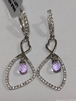 Pair of silver earrings with purple amethyst drops and clear stones shown from front.