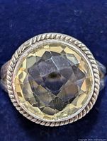 Top view of the ring showcasing the light yellow faceted round citrine gemstone with twisted rope bezel setting on silver band.