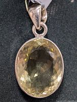 Clear close-up photo of the oval lemon quartz gemstone set in silver, viewed frontally with emphasis on faceting and color.