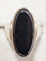 Top-down clear shot of the large oval black onyx gemstone bezel set in polished sterling silver ring band.
