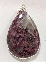 Front view of the teardrop shaped pendant showing purple, black, and gray gemstone set in silver.