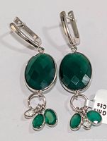 Photo showing front view of silver earring with large faceted oval green onyx stone and three dangling smaller green onyx stones attached to a lever-back clasp.
