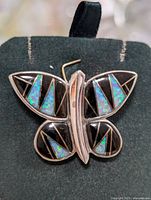 Front view of silver butterfly pendant with detailed inlay stones showcasing design and colors.