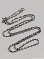 Close-up of the silver chain necklace showing chain links and overall design.