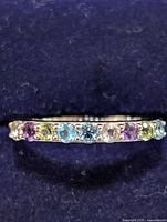 Front view of a sterling silver ring with multi-colored gemstones in a row on the band.