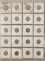 Twenty Canadian 5 cent coins individually housed in paper holders with clear windows showing front and back of each coin with visible years from early 1950s to early 1960s.