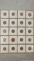 Twenty Canadian 5-cent coins from 1961, 1962, and 1963 in individual cardboard coin holders, arranged in rows on a flat surface.