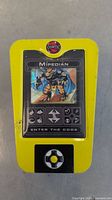 Yellow handheld electronic device featuring a Mipedian character card image and control button for entering card codes